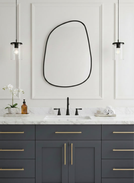 Asymmetrical brass mirror above bathroom vanity