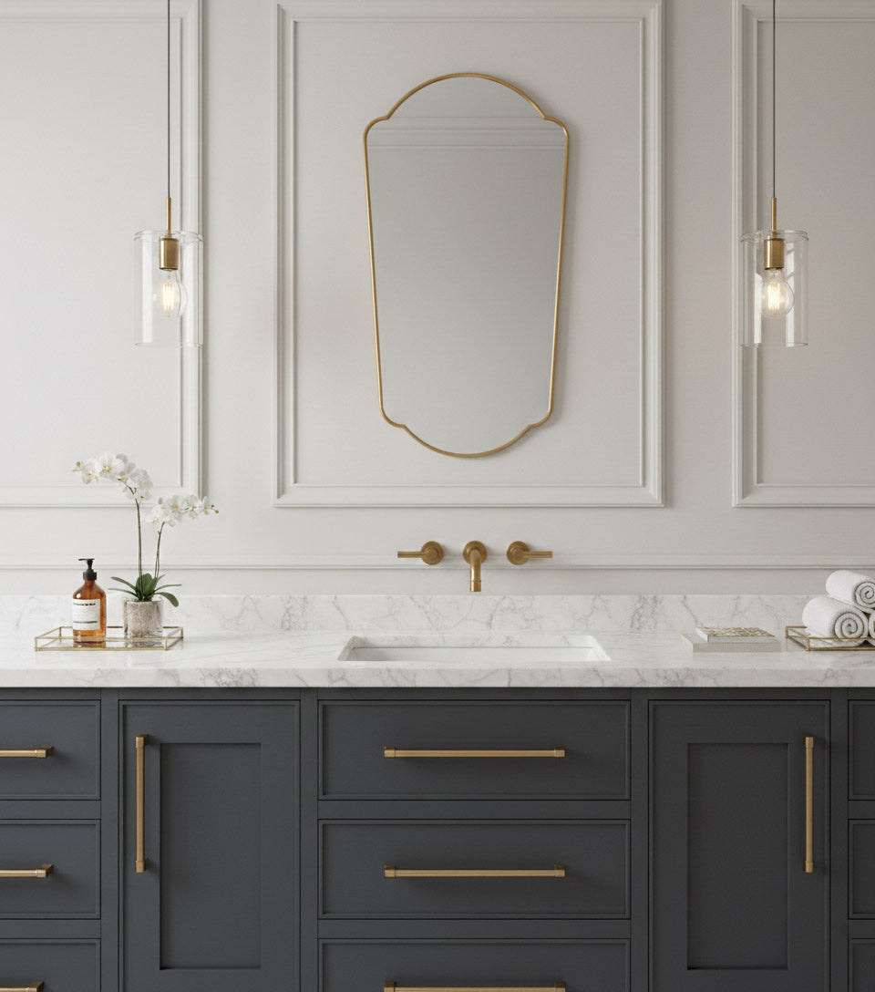 Arched full length brass mirror above marble bathroom vanity.