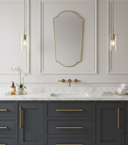 Arched full length brass mirror above marble bathroom vanity.