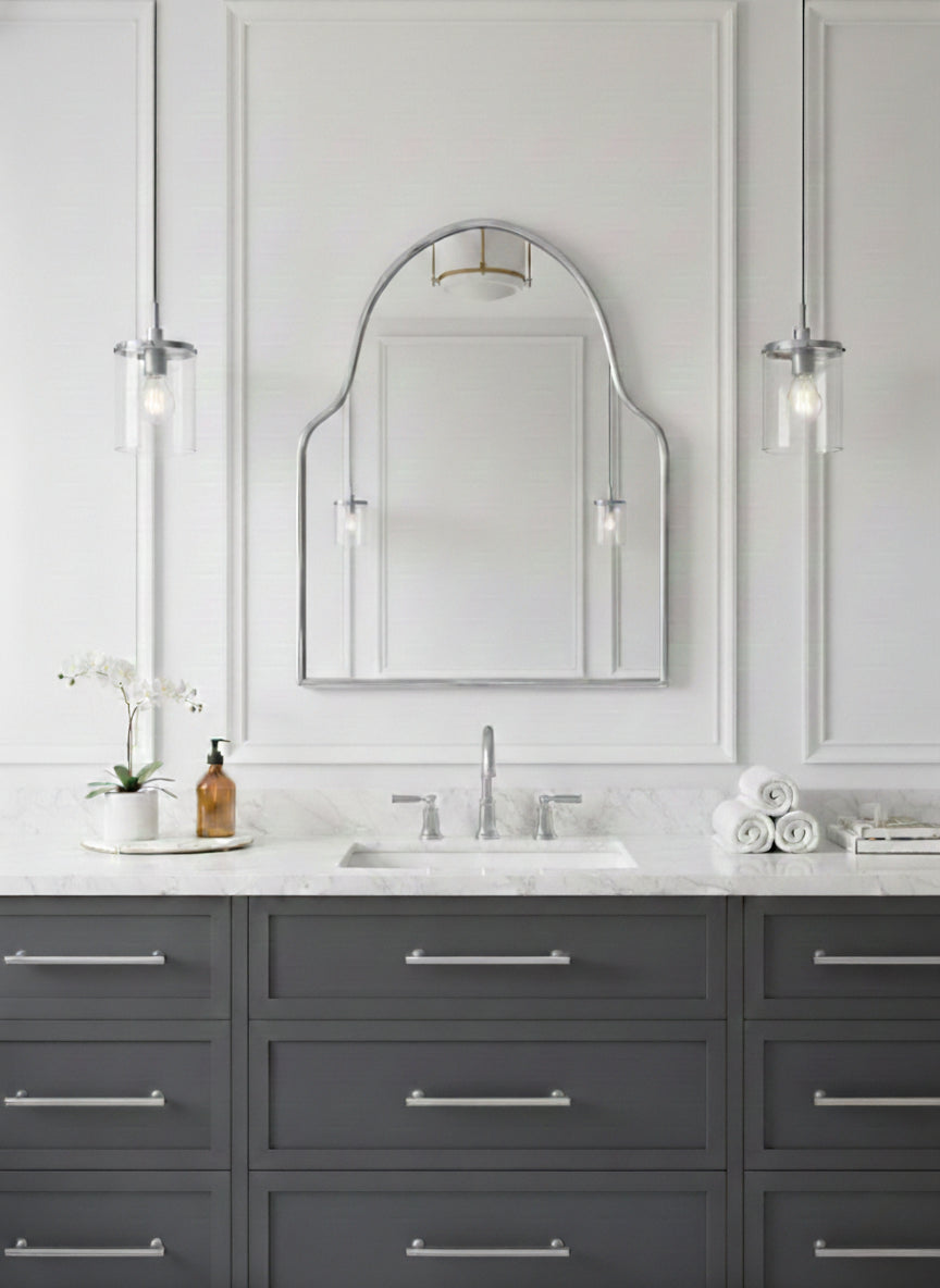 Silver brass arch mirror above marble bathroom vanity with pendant lights.