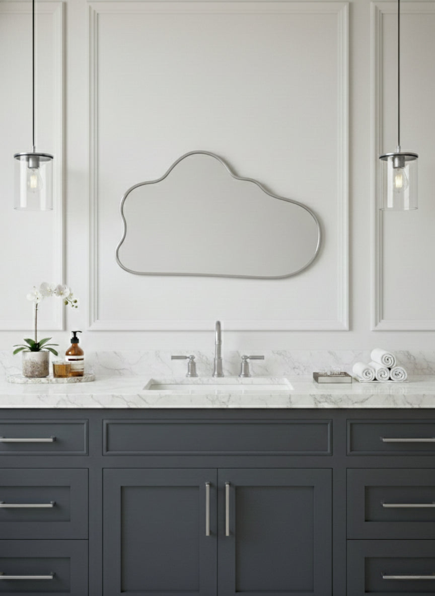 Silver brass cloud mirror above gray vanity with marble countertop.