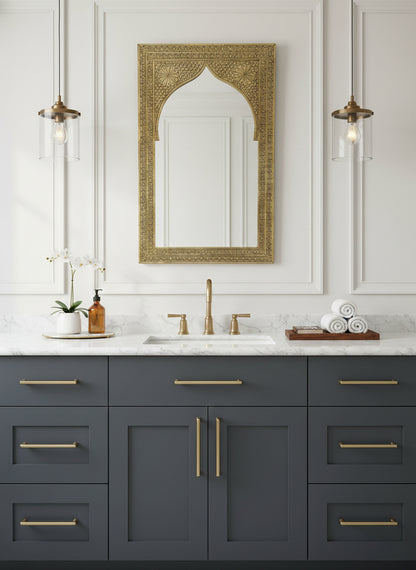 Carved arch brass mirror above a bathroom vanity