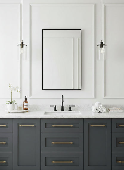 Modern black rectangular bathroom mirror over gray vanity with brass handles.