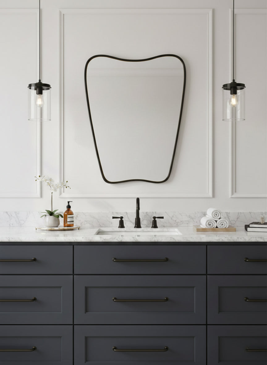 Irregular black framed mirror over gray bathroom vanity with pendant lights.