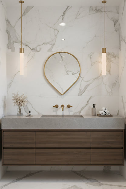Teardrop brass mirror above wood vanity with marble wall