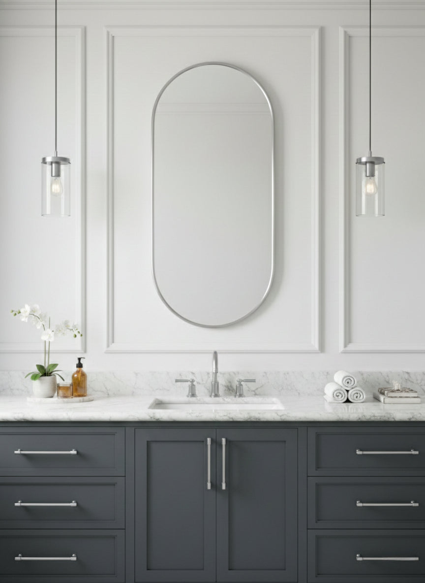 Silver capsule mirror over gray vanity with marble countertop.