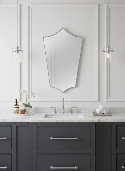 Silver brass shield mirror over gray vanity with marble countertop.