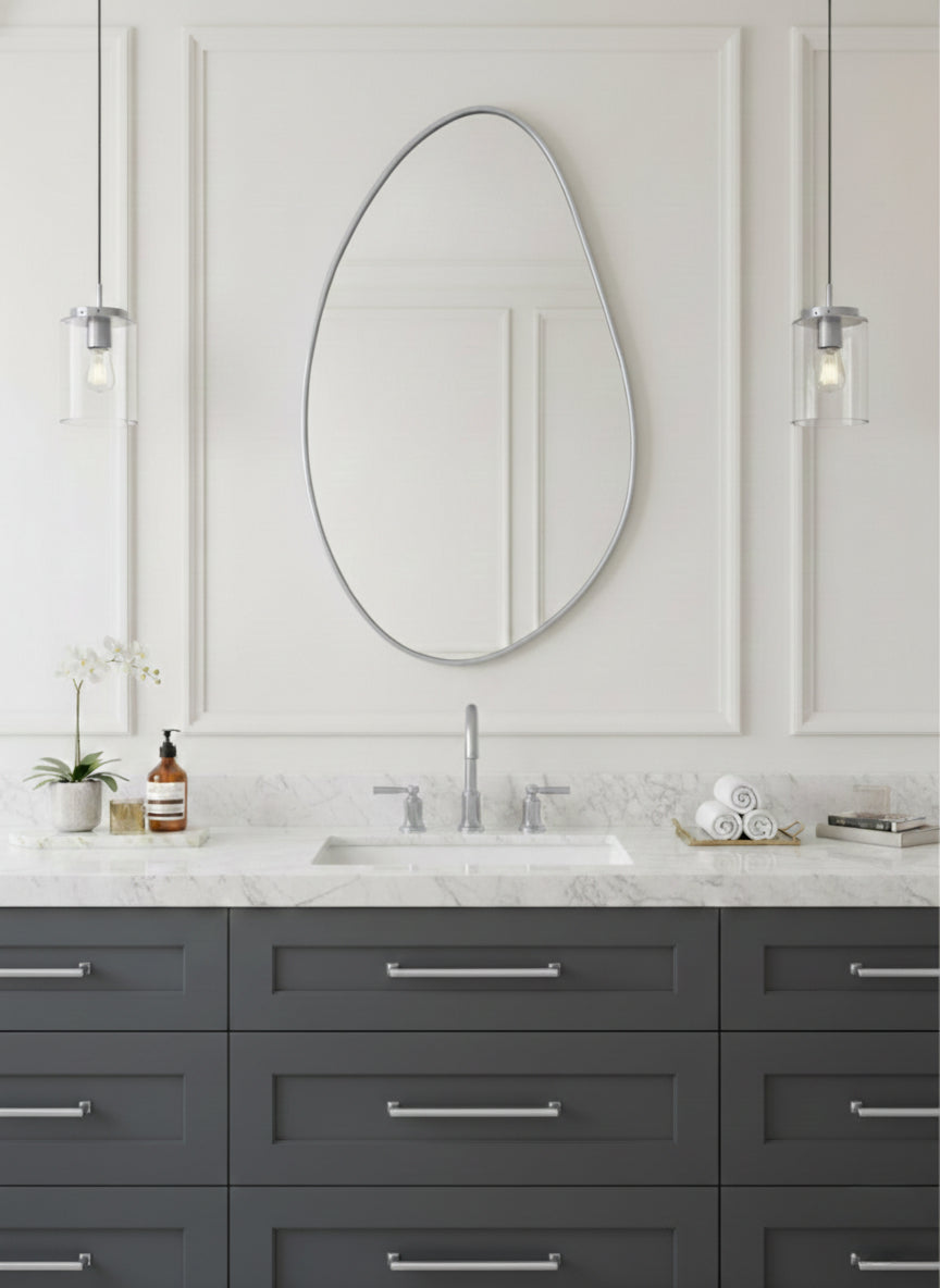Silver asymmetrical brass mirror over gray vanity.