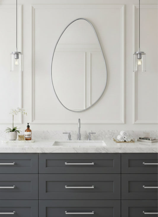Silver asymmetrical brass mirror over gray vanity.