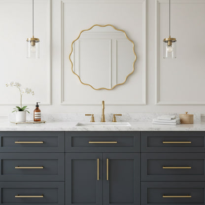 Round wavy gold mirror over gray vanity in elegant white bathroom.