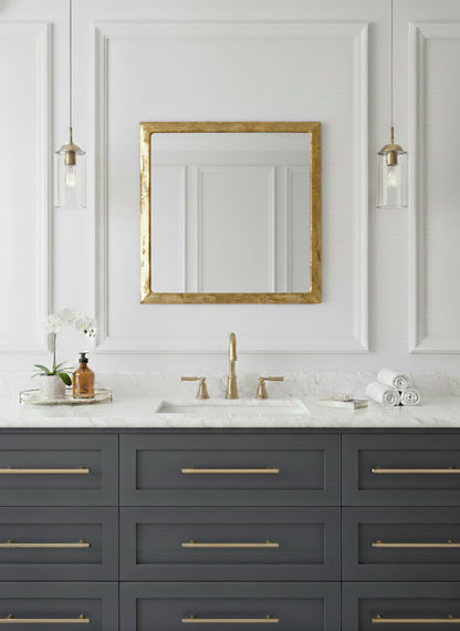Gold square mirror over modern bathroom vanity with brass fixtures
