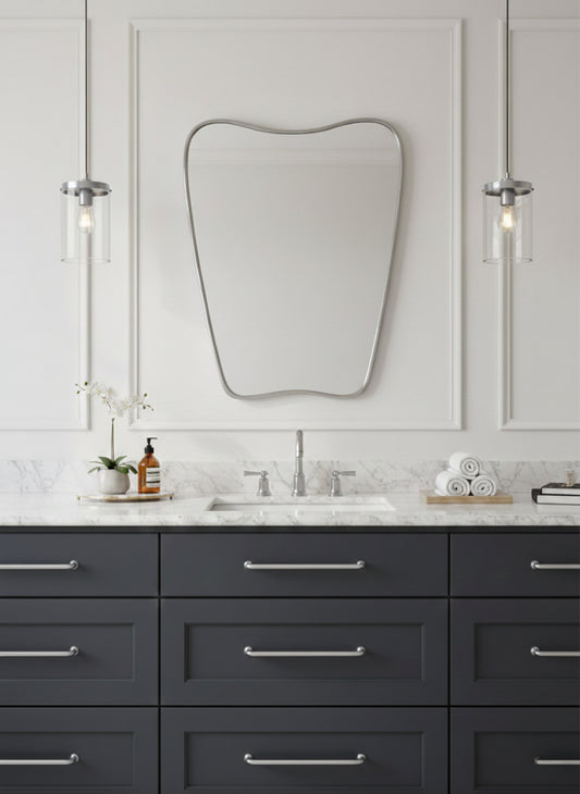 Asymmetrical brass mirror above marble bathroom vanity with pendant lights.