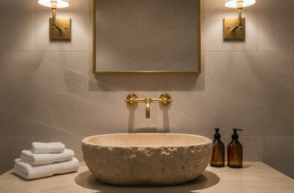 Centered brass wall faucet with stone vessel sink and brass-framed mirror.