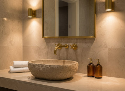 Natural stone basin with brass wall faucet and warm lighting