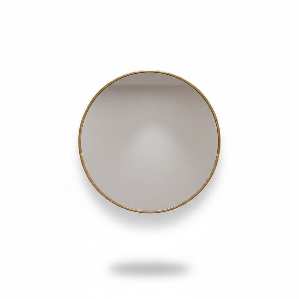 Round brass wall mirror with thin gold frame on white background