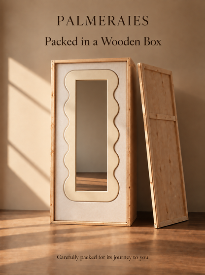 A wooden-framed mirror cabinet with a wavy rectangular mirror and a separate wooden back panel leaning beside it, set in a warm neutral room with text reading 'PALMERAIES Packed in a Wooden Box' and 'Carefully packed for its journey to you.'.