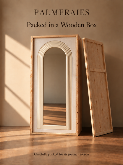 A tall rectangular wooden box with a large arched mirror on the front and a separate wooden panel leaning against it, shown in a warm neutral room. Text at the top reads 'PALMERAIES Packed in a Wooden Box' and small text at the bottom says 'Carefully packed for its journey to you'.