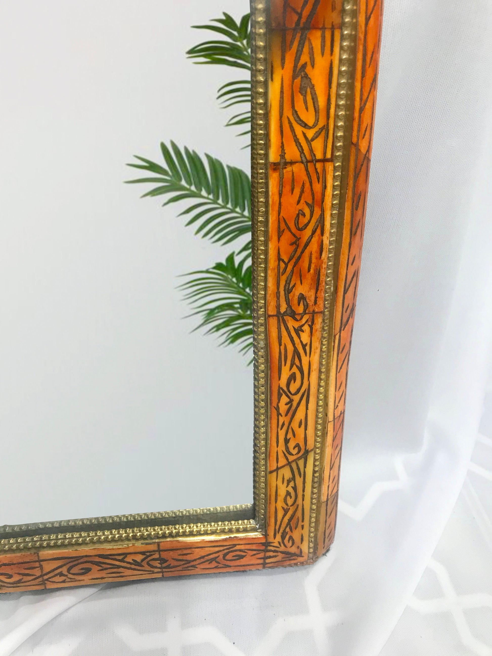 a mirror sitting on top of a table next to a plant