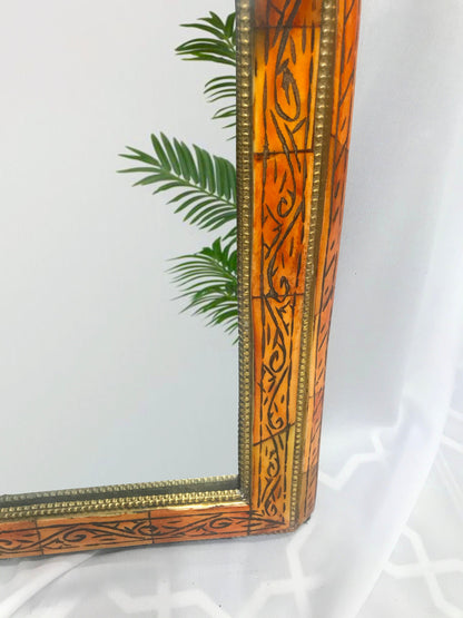 a mirror sitting on top of a table next to a plant