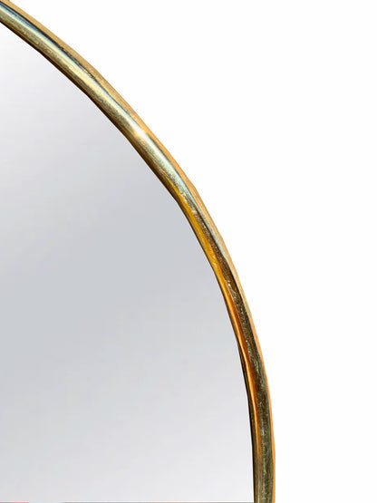 a mirror with a curved gold frame on a white background