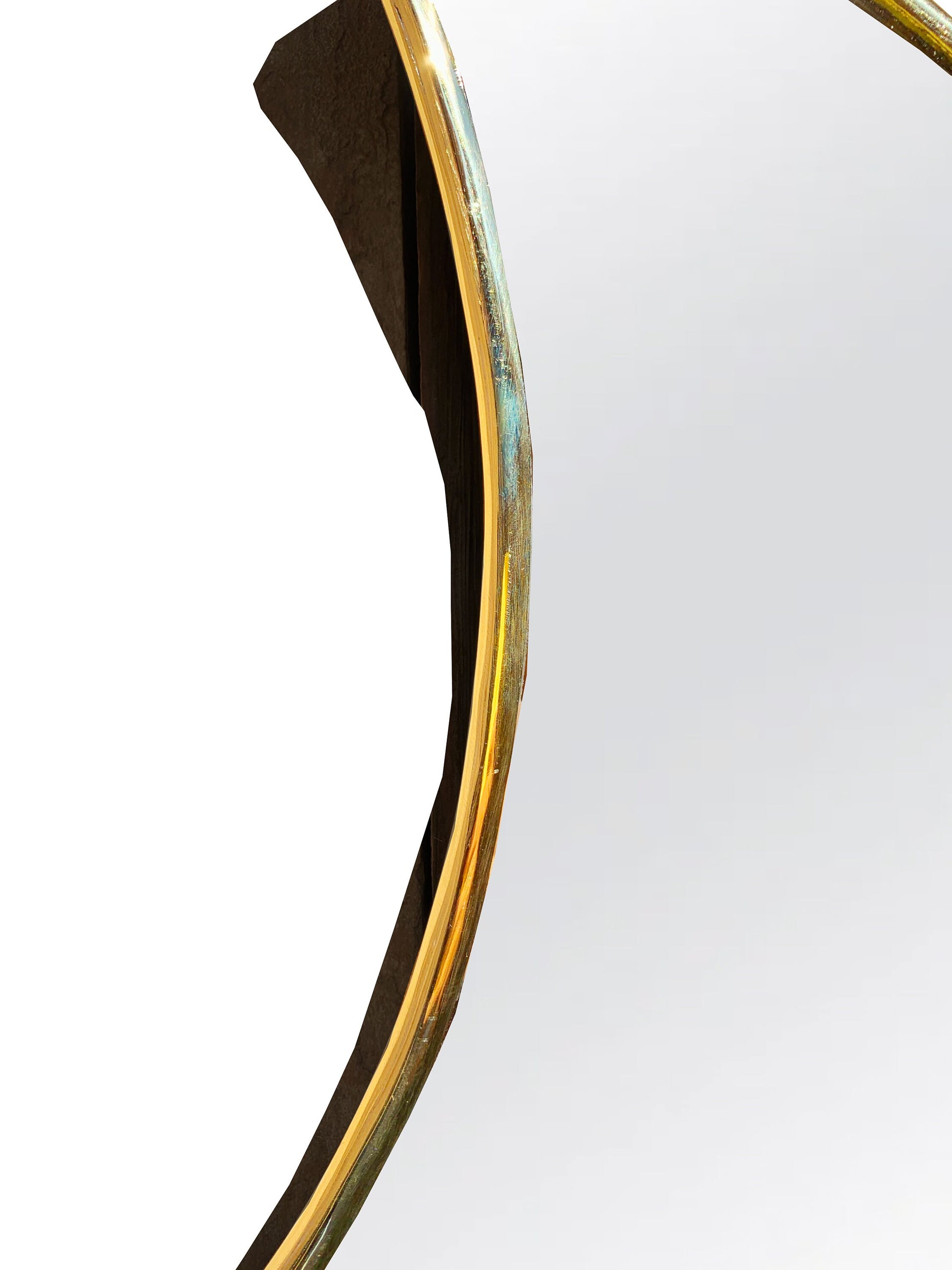 a mirror with a curved gold frame and a white background