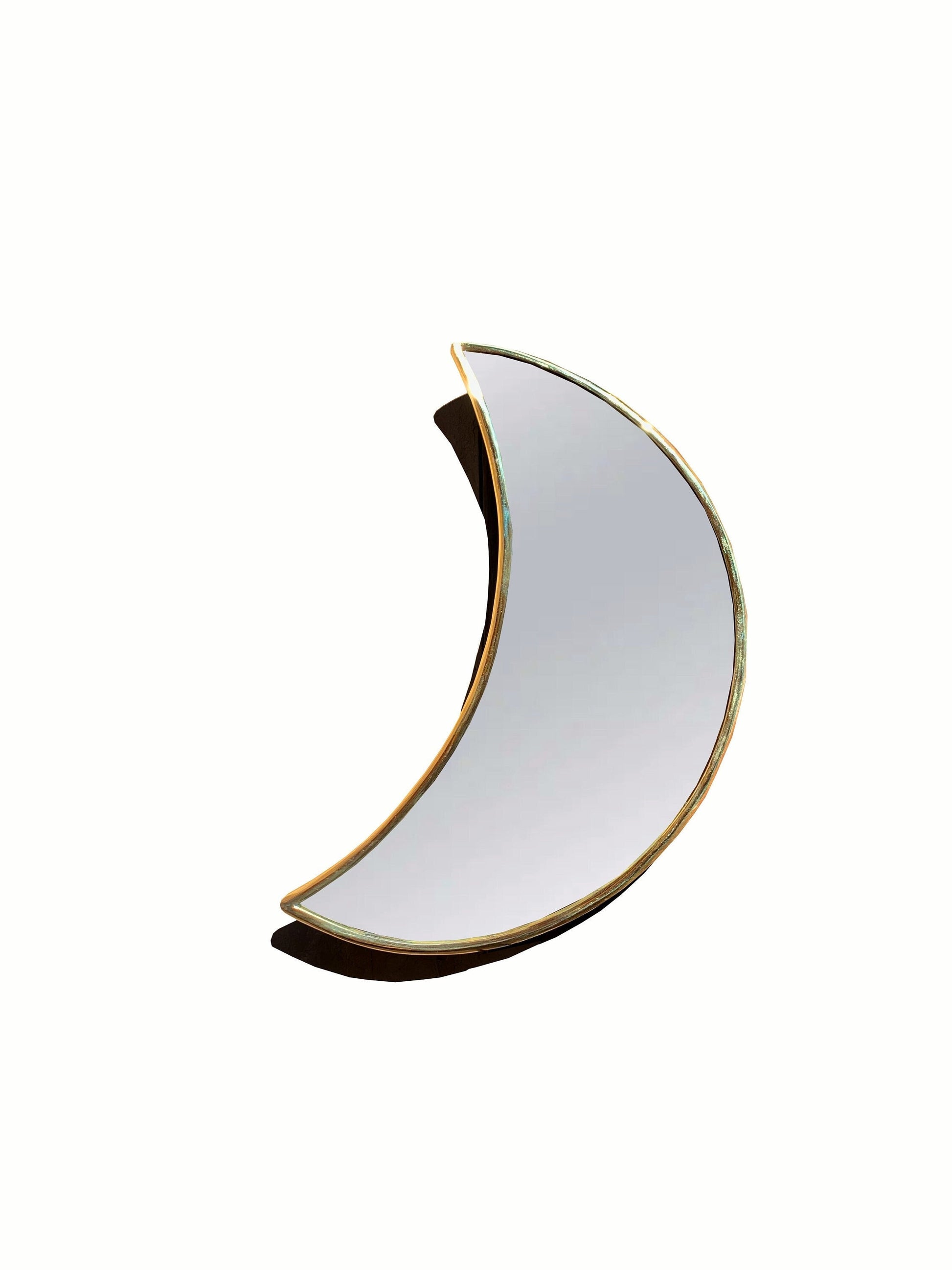 a white and gold crescent shaped mirror against a white background