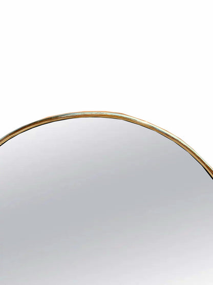 a round mirror with a gold rim on a white background