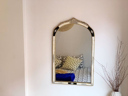 a vintage mirror hanging on a wall above a bed