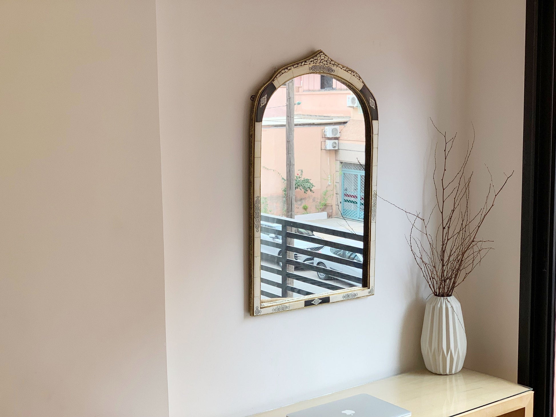 a mirror on a wall above a desk with a laptop