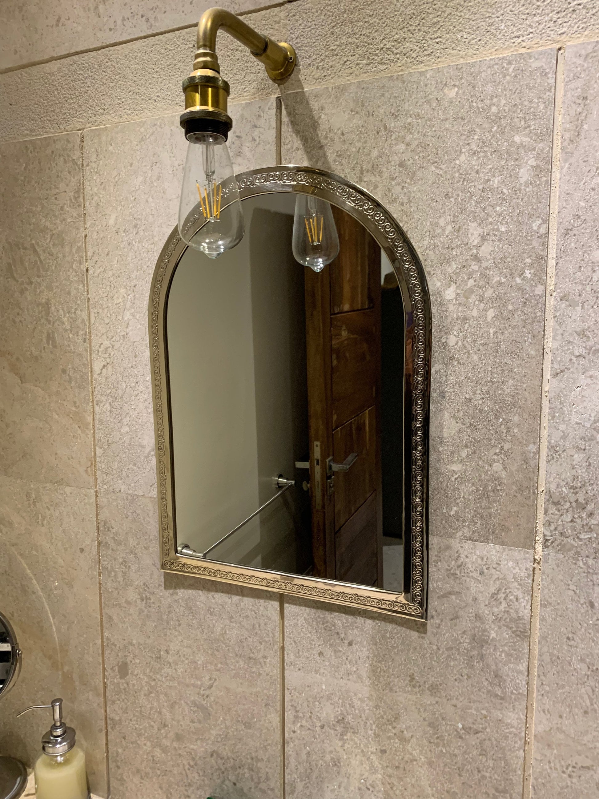 a bathroom with a sink, mirror and soap dispenser