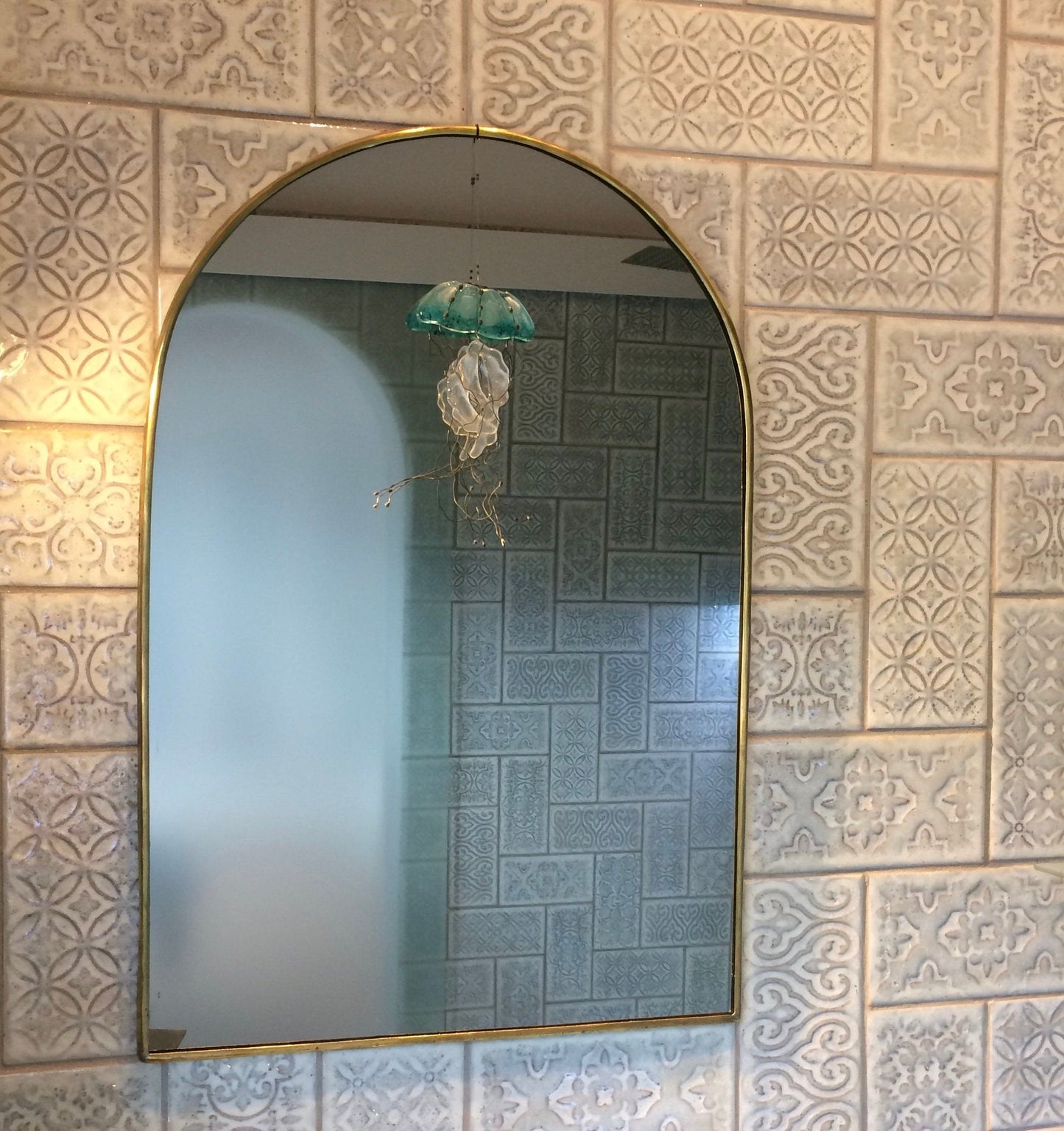 a bathroom with a sink and a arch mirror