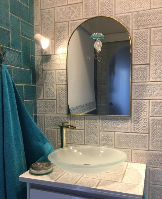 a bathroom with a sink and a brass mirror