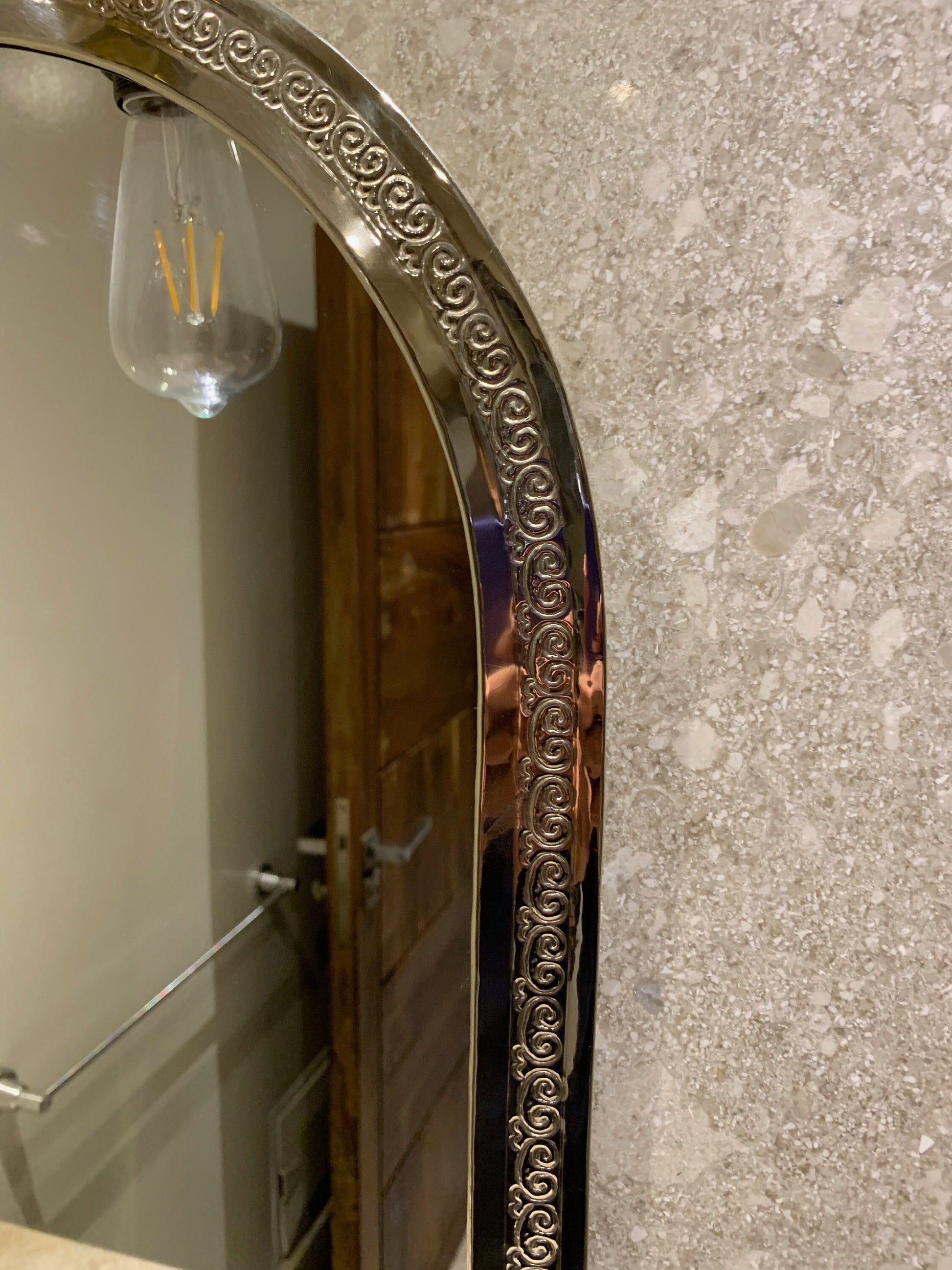 a bathroom mirror with a wine glass hanging from it's side