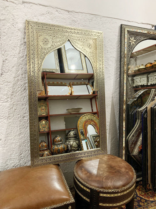 a mirror sitting on top of a table next to a stool