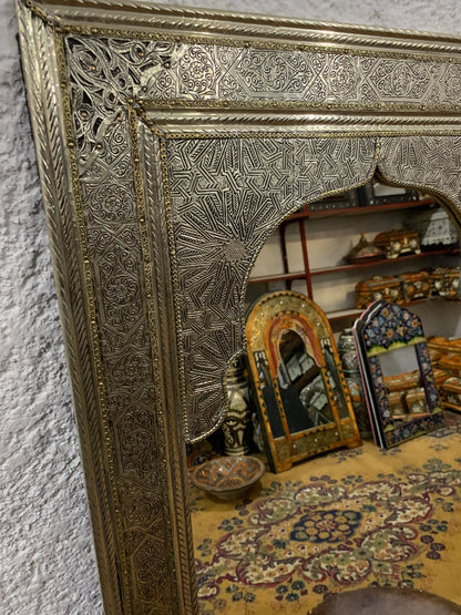 a gold framed mirror sitting on top of a table