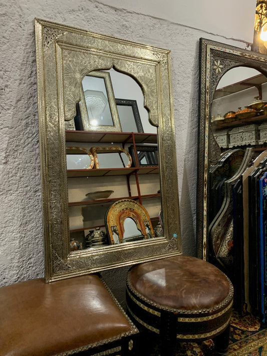 a mirror sitting on top of a table next to a stool