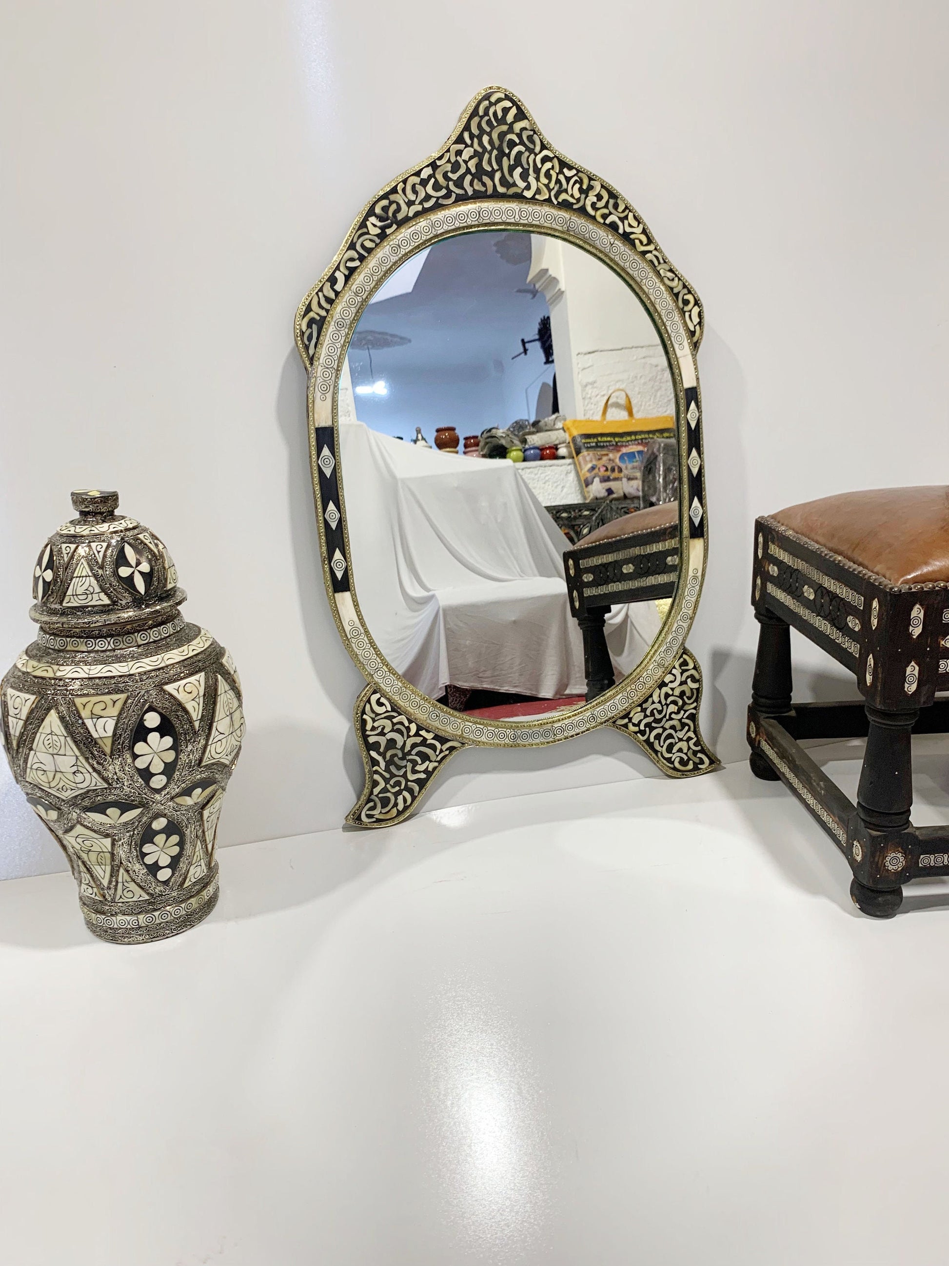 a mirror sitting on top of a table next to a vase