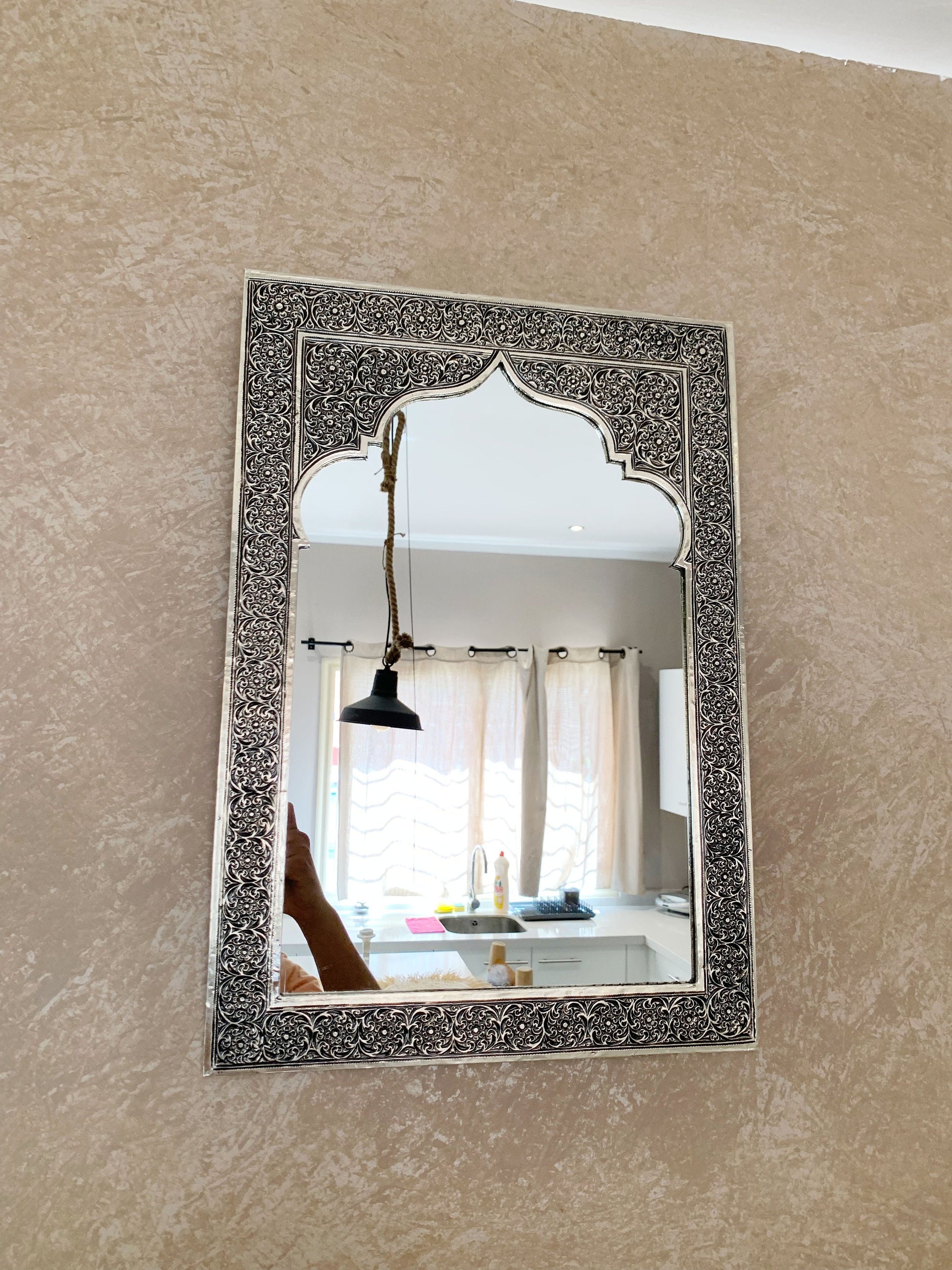 a mirror hanging on a wall above a sink