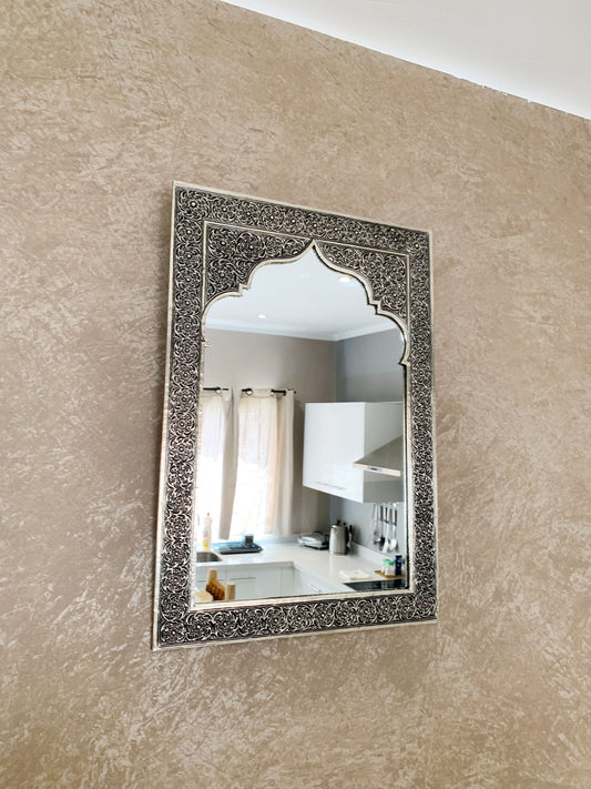 a mirror hanging on a wall above a sink