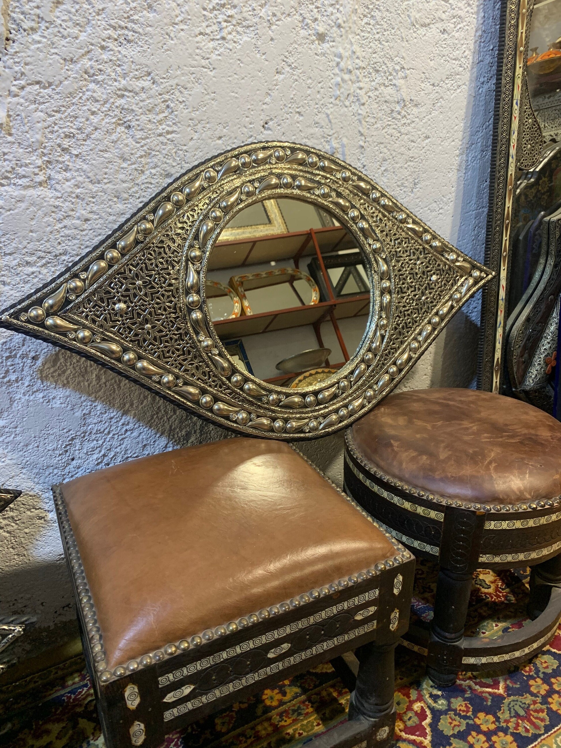 a mirror sitting on top of a table next to two stools