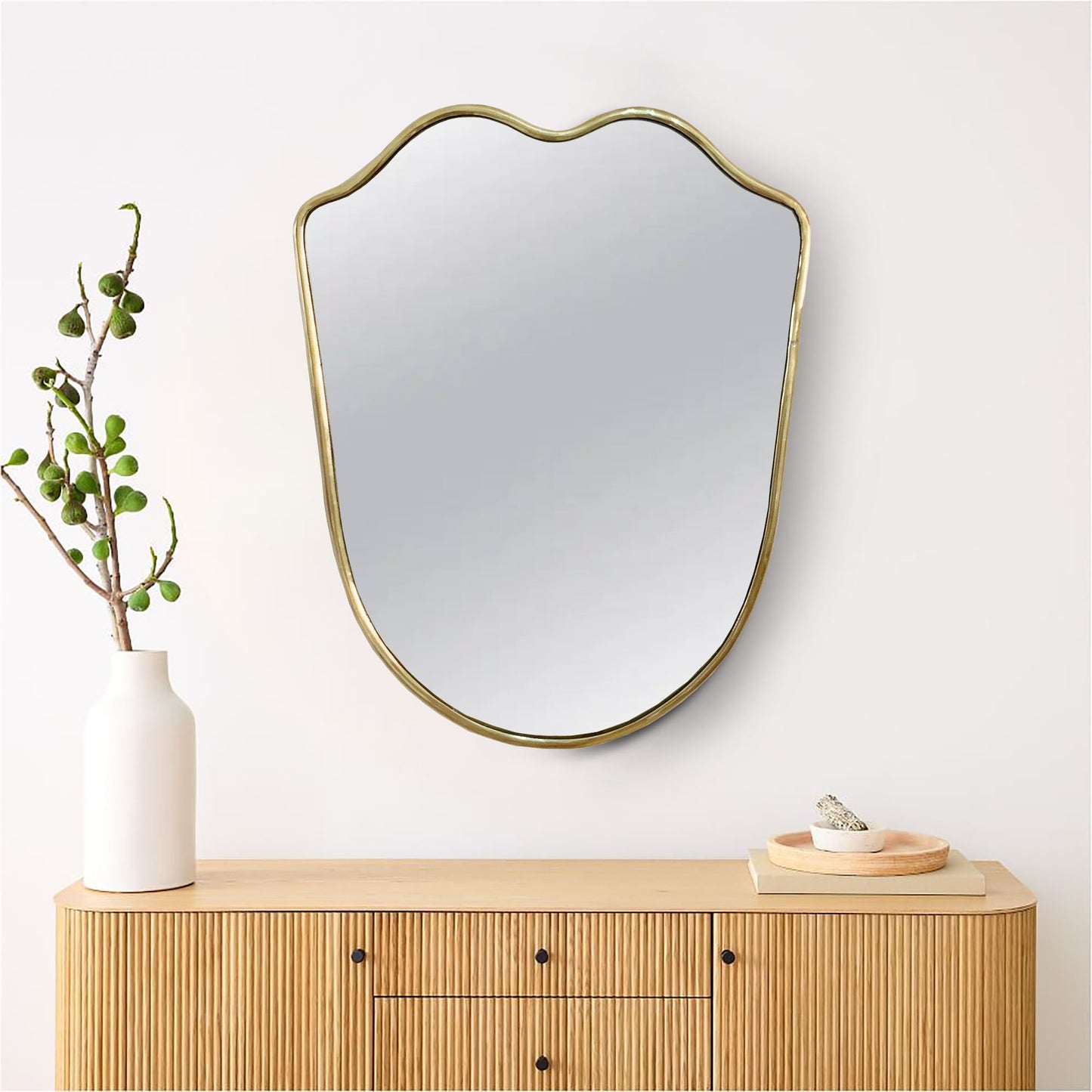 a brass mirror sitting on top of a wooden dresser