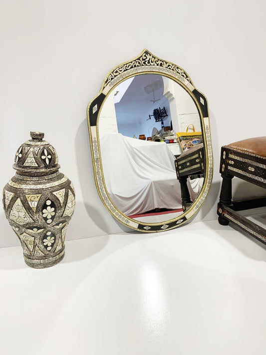 a mirror sitting on top of a table next to a vase