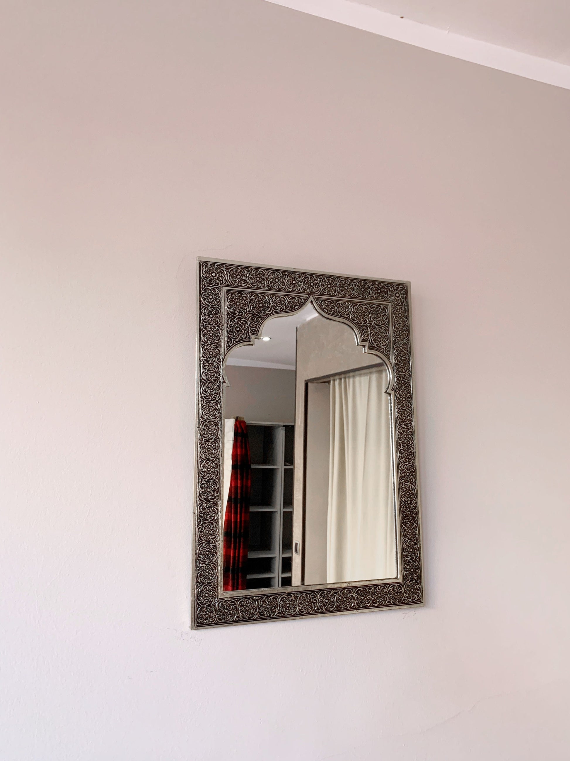 a mirror hanging on a wall above a bed