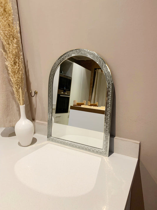 a mirror sitting on top of a counter next to a vase