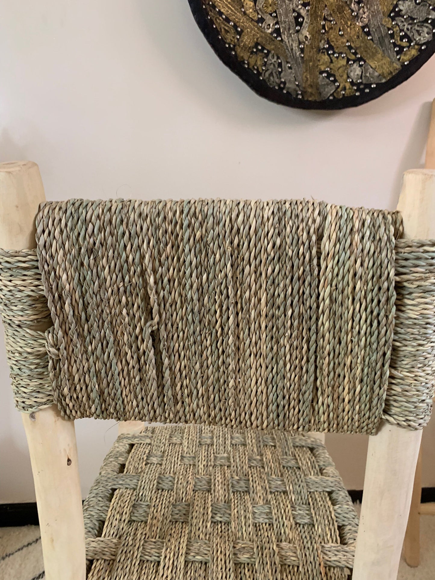 a wicker chair sitting in front of a wall