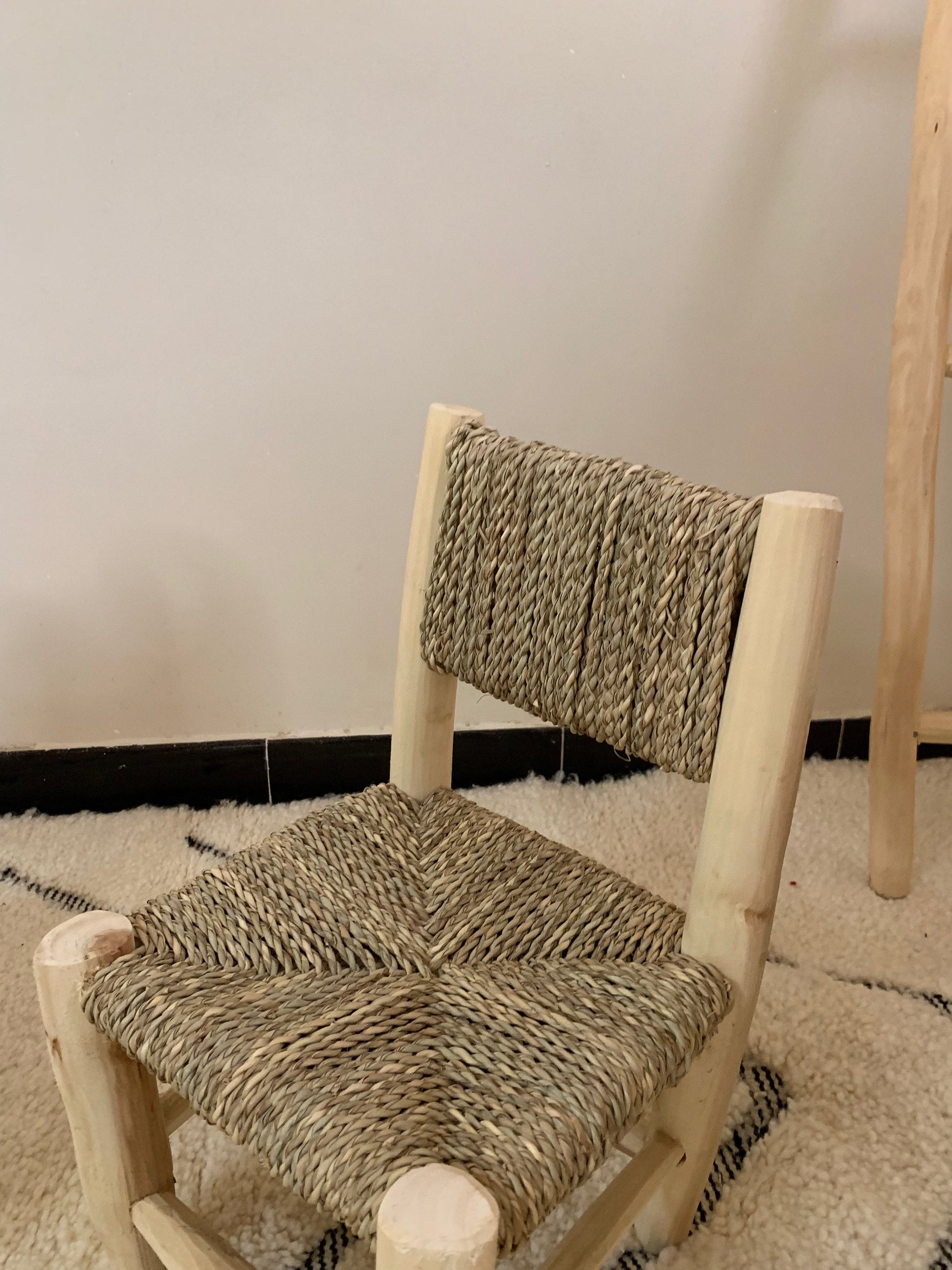 a wooden chair with a woven seat on a rug