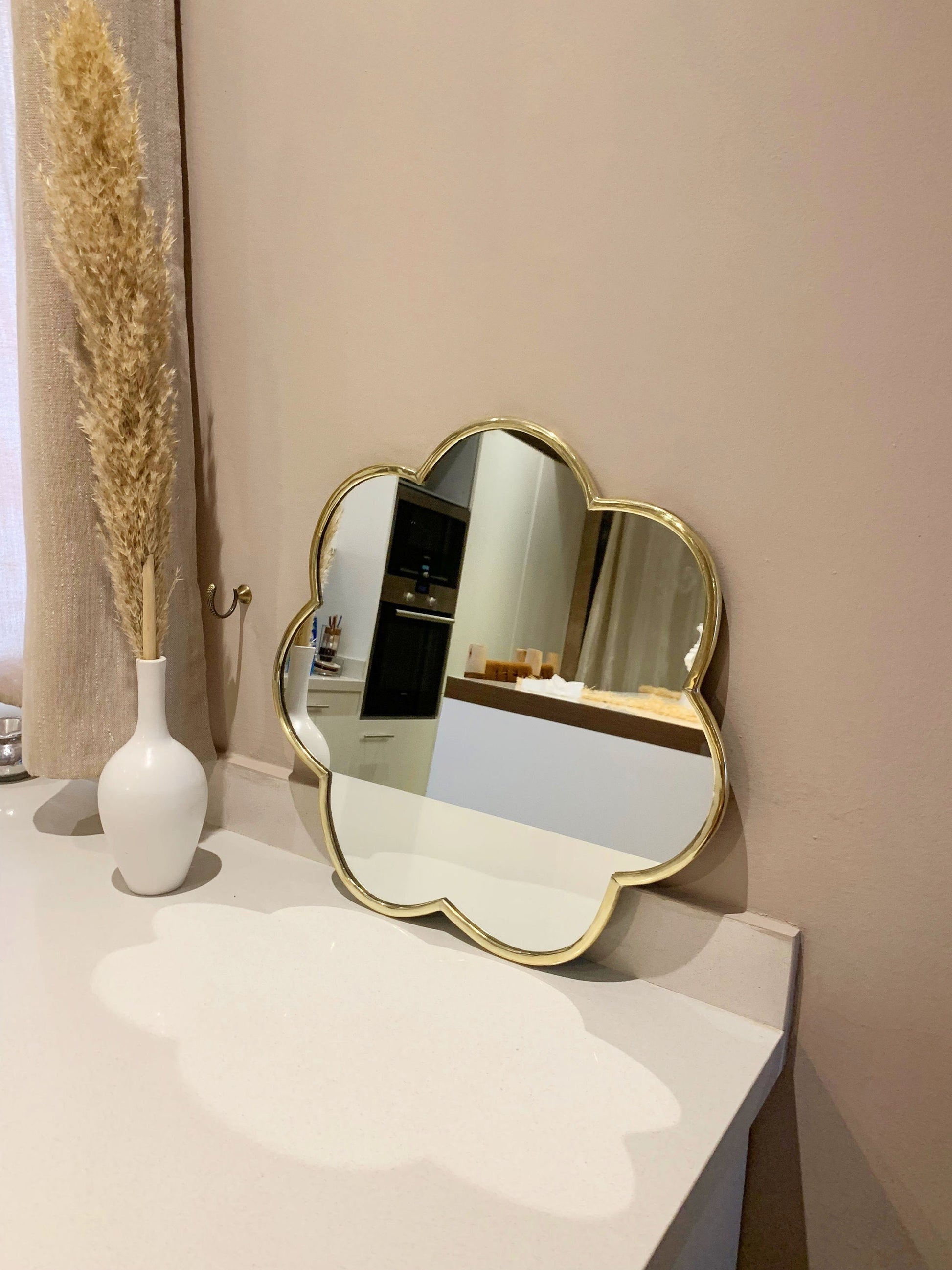 a flower brass mirror sitting on top of a white counter