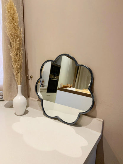 a mirror sitting on top of a white counter next to a vase