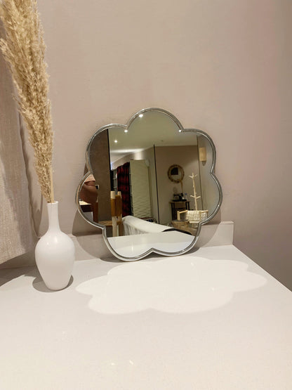 a white vase sitting on top of a table next to a mirror