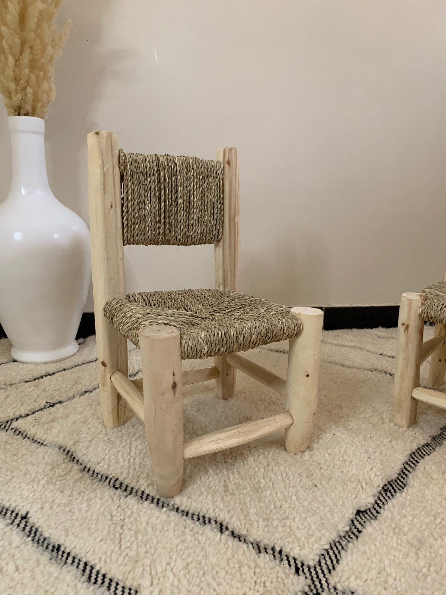 a white vase sitting next to a wooden chair